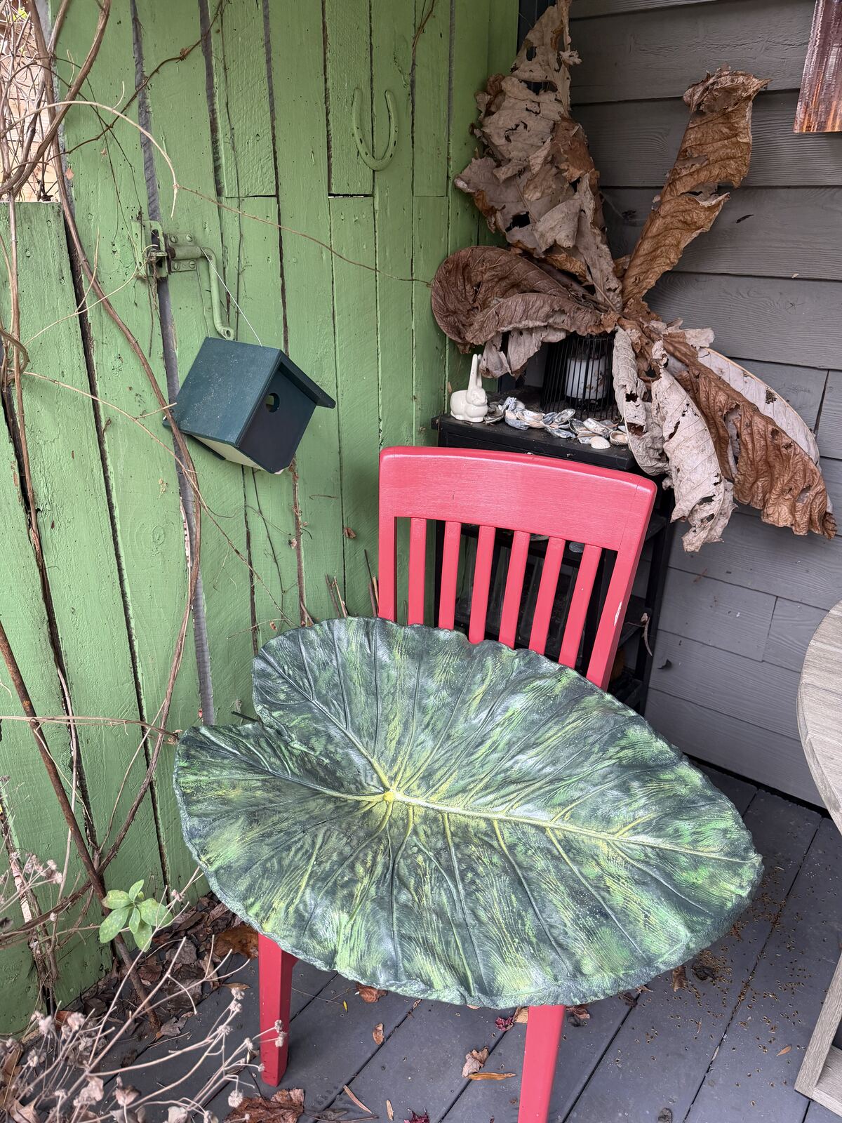 The painted cast propped on a red chair beside the dried real Colocasia leaves