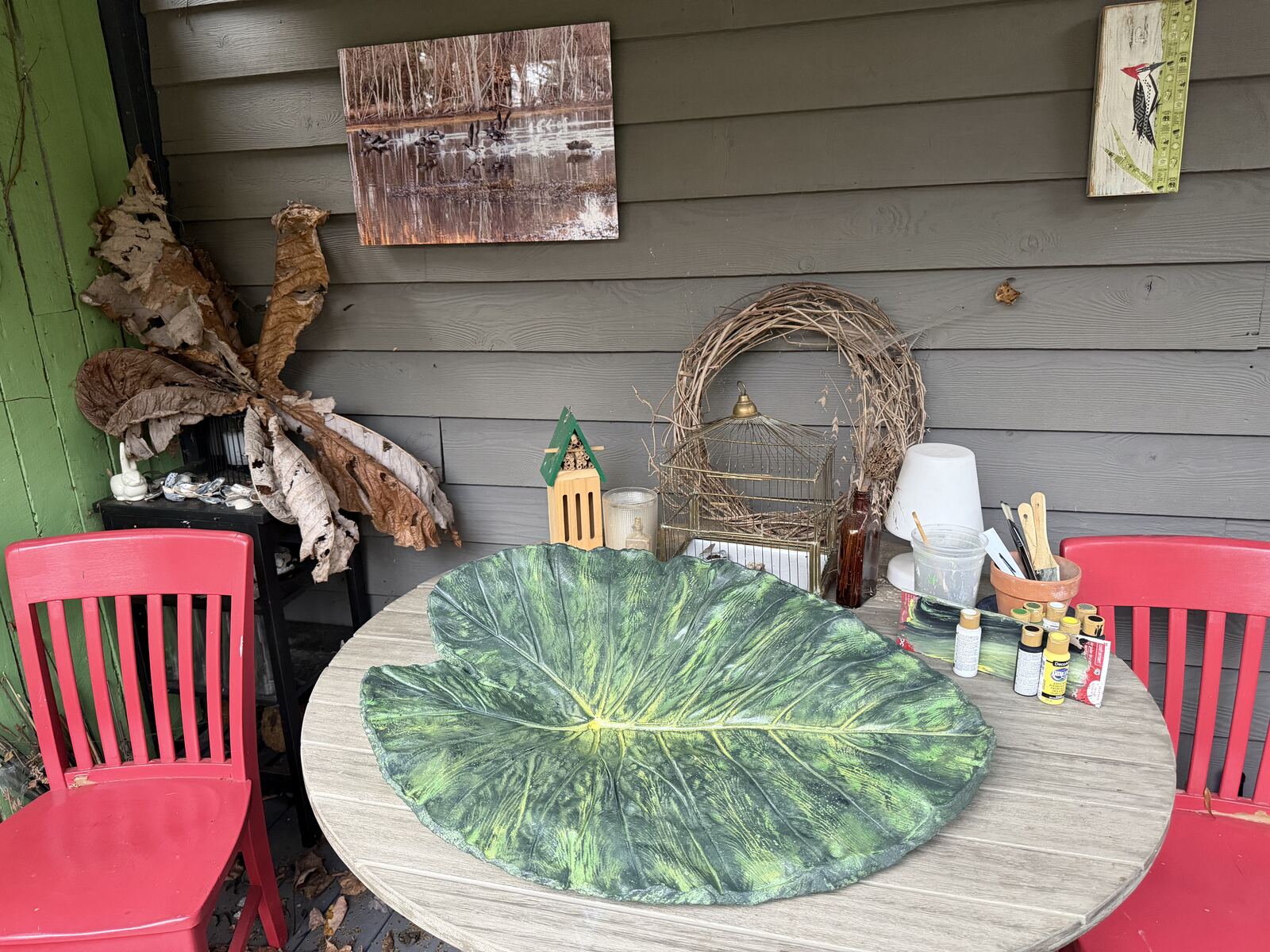 The cast displayed on a porch table with paints and a birdcage